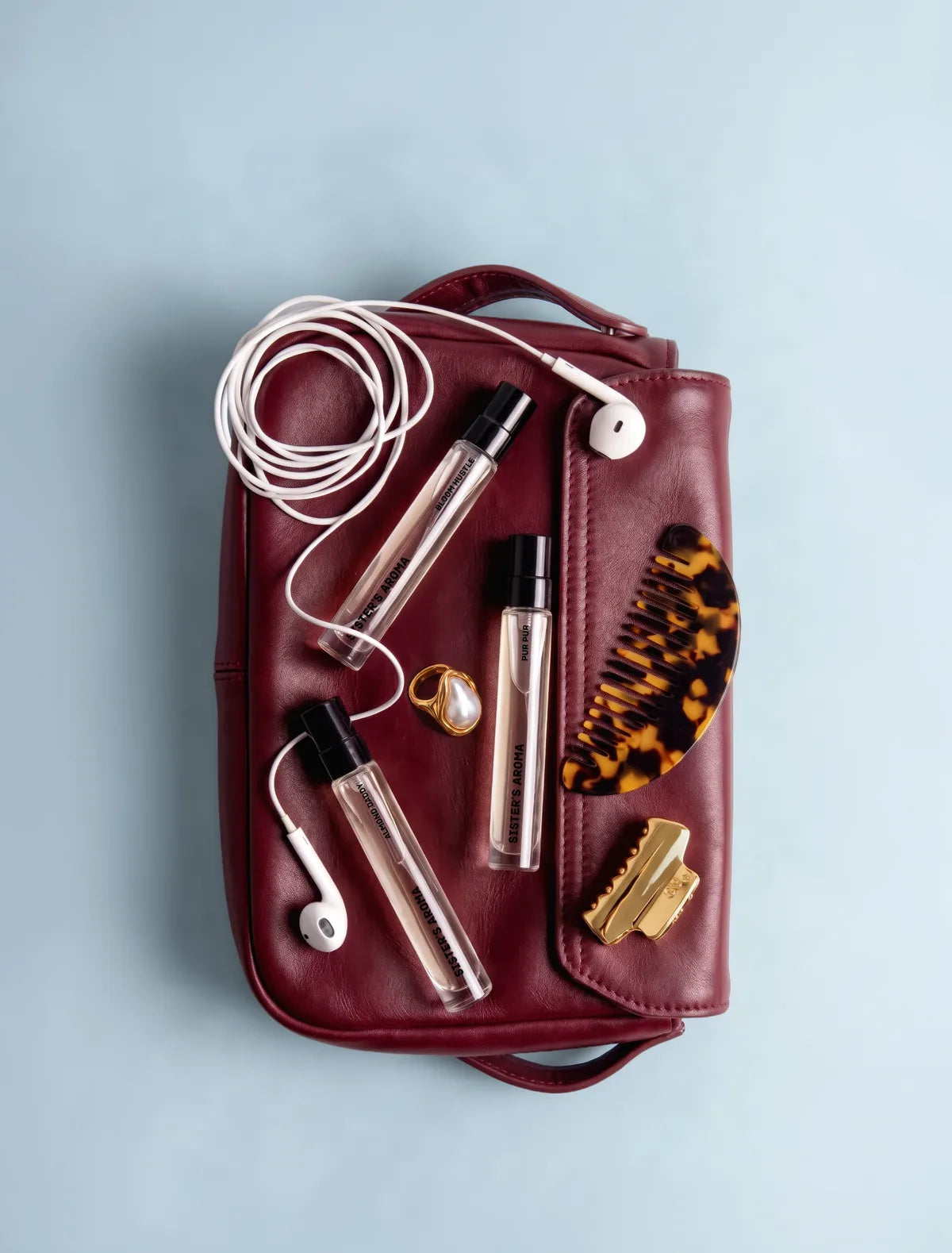 Sister’s Aroma perfumes in a burgundy cosmetic bag